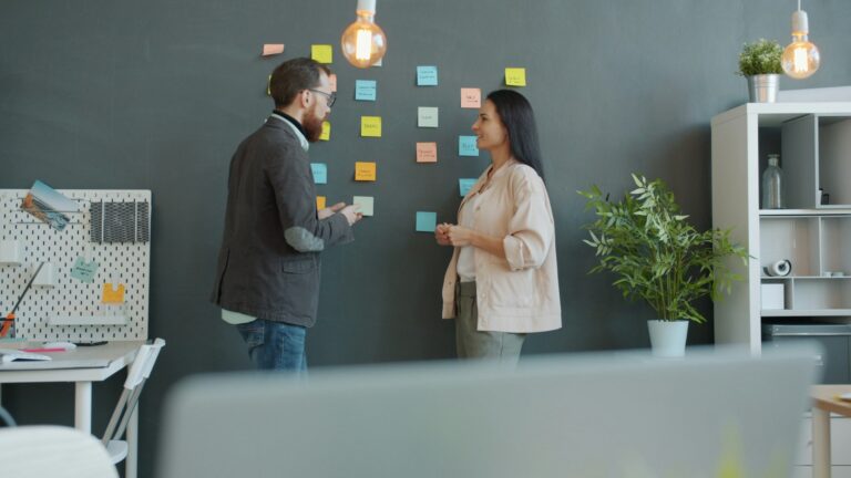 Man och kvinna som pratar i ett kontor, med post-it lappar i bakgrunden