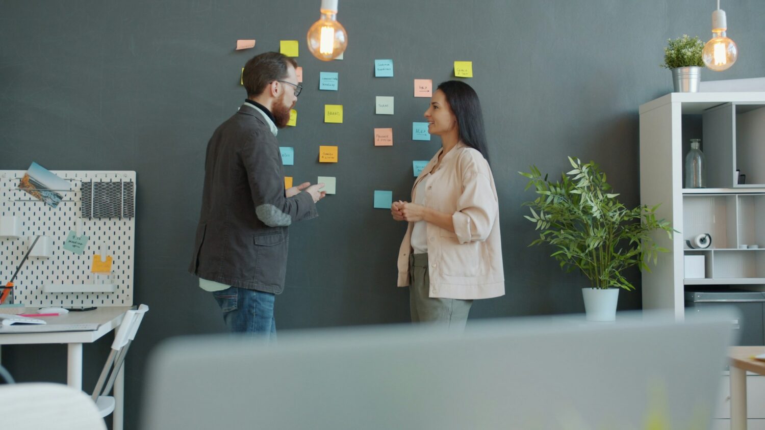 Man och kvinna som pratar i ett kontor, med post-it lappar i bakgrunden